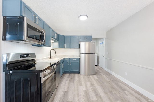 kitchen featuring light hardwood / wood-style floors, sink, a textured ceiling, stainless steel appliances, and blue cabinets