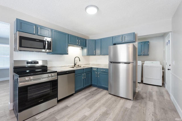 kitchen with sink, stainless steel appliances, washing machine and dryer, and blue cabinets