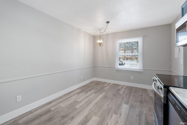 unfurnished dining area featuring light wood-type flooring, an inviting chandelier, and a textured ceiling