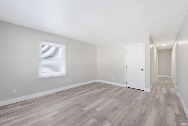 empty room featuring a textured ceiling and light hardwood / wood-style floors