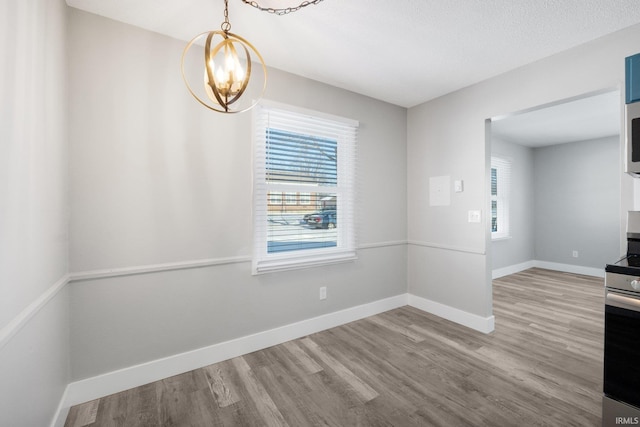 unfurnished dining area featuring a notable chandelier and hardwood / wood-style floors