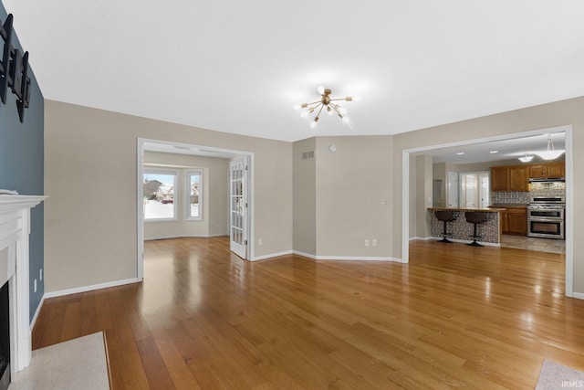 unfurnished living room featuring light hardwood / wood-style floors and a notable chandelier