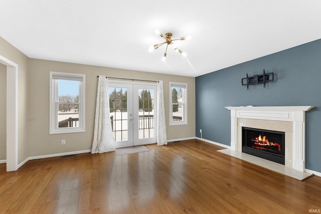 unfurnished living room featuring wood-type flooring, french doors, and a notable chandelier