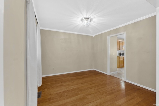 unfurnished room featuring crown molding, a chandelier, and light hardwood / wood-style floors