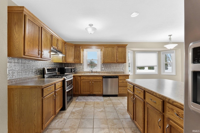 kitchen featuring appliances with stainless steel finishes, sink, hanging light fixtures, backsplash, and light tile patterned floors