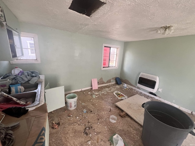 interior space featuring heating unit and a textured ceiling