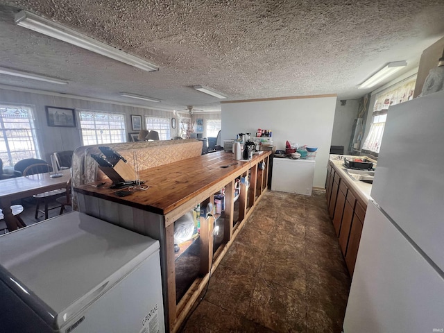 kitchen featuring wooden counters, a textured ceiling, sink, and white fridge