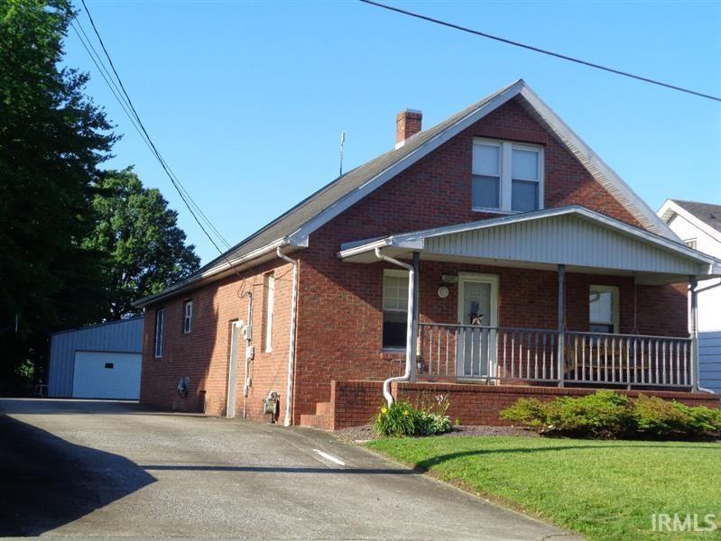 bungalow-style home with a garage, a front yard, an outbuilding, and a porch