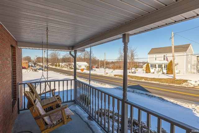 snow covered back of property featuring a porch