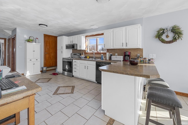 kitchen featuring white cabinetry, stainless steel appliances, decorative backsplash, sink, and kitchen peninsula