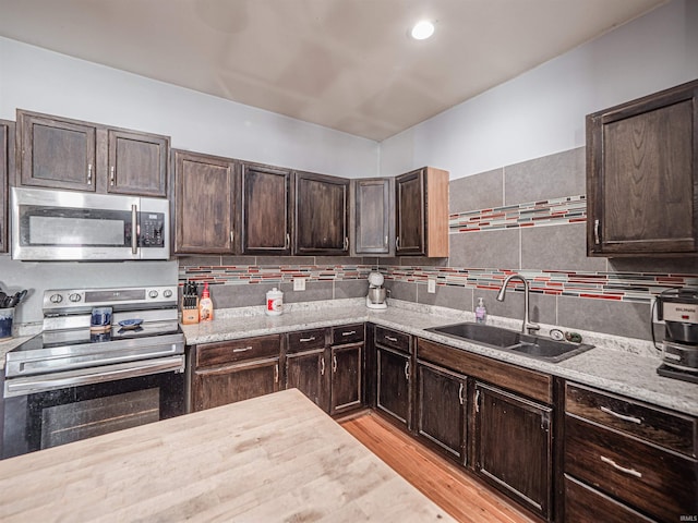 kitchen with light wood-type flooring, appliances with stainless steel finishes, sink, and dark brown cabinetry