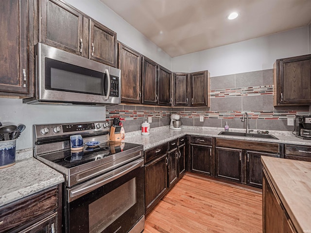 kitchen with light hardwood / wood-style floors, wooden counters, appliances with stainless steel finishes, dark brown cabinetry, and sink