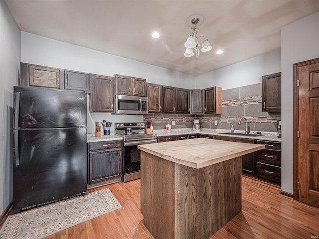 kitchen featuring pendant lighting, wooden counters, a kitchen island, stainless steel appliances, and sink