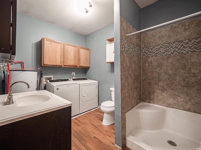 bathroom with toilet, vanity, independent washer and dryer, hardwood / wood-style floors, and a tile shower