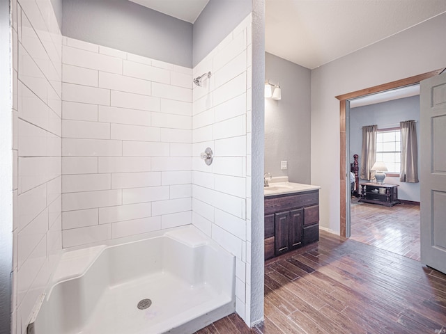 bathroom featuring vanity, wood-type flooring, and a tile shower