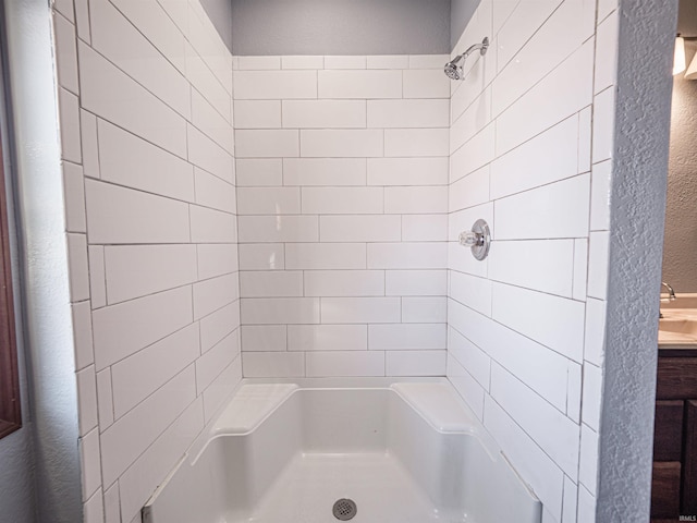 bathroom with tiled shower and sink