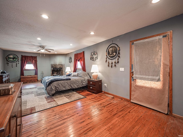 bedroom with a textured ceiling, ceiling fan, and light wood-type flooring