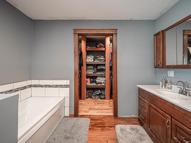 bathroom featuring vanity, a bathtub, a textured ceiling, and hardwood / wood-style floors