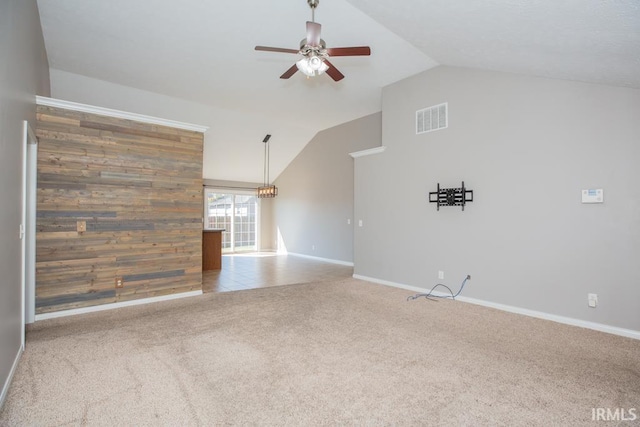 unfurnished living room with ceiling fan, lofted ceiling, light colored carpet, and wooden walls