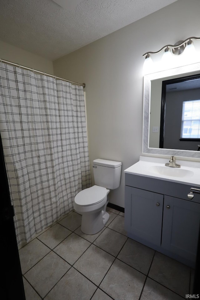 bathroom with a textured ceiling, toilet, vanity, and tile patterned flooring