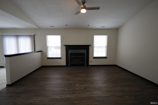 unfurnished living room with ceiling fan, a textured ceiling, and dark hardwood / wood-style floors