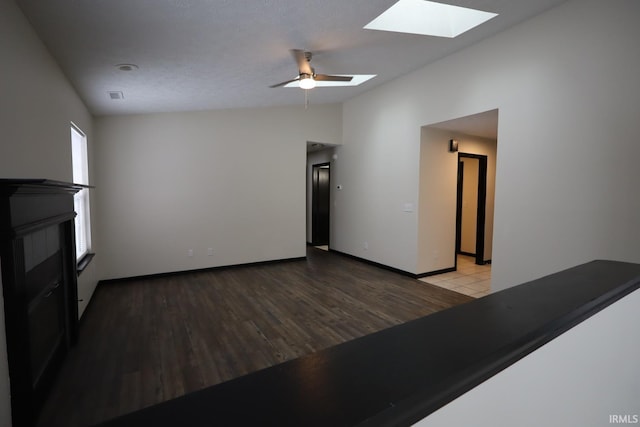 unfurnished living room with ceiling fan, lofted ceiling with skylight, and light hardwood / wood-style floors