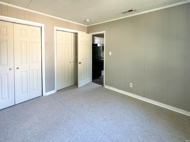 unfurnished bedroom with black refrigerator, carpet floors, and ornamental molding