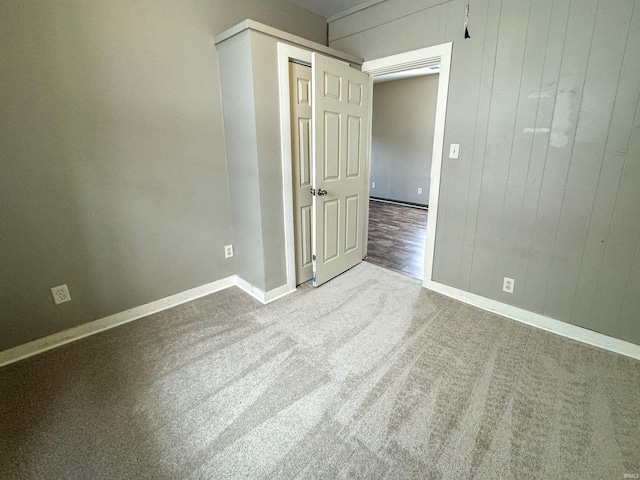 carpeted empty room featuring wood walls