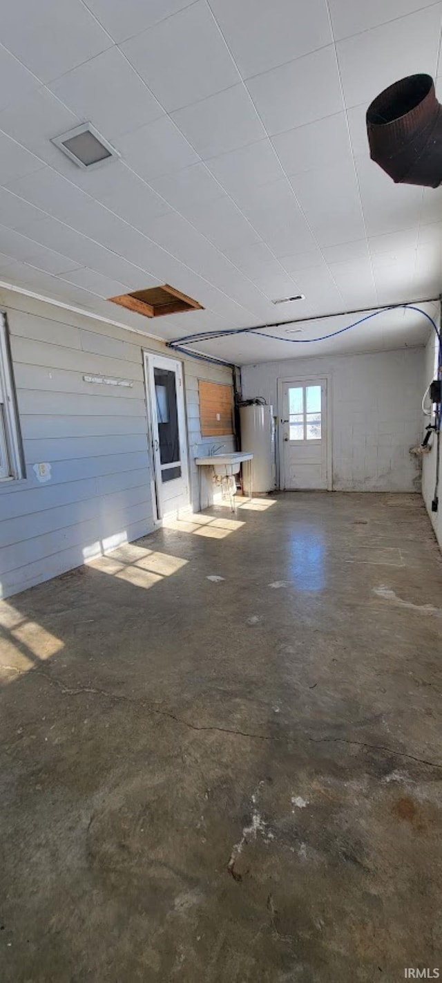 interior space with a garage door opener, wood walls, and gas water heater