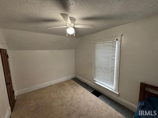 bonus room with a textured ceiling, carpet floors, plenty of natural light, vaulted ceiling, and ceiling fan