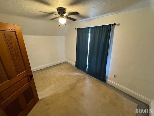 additional living space featuring a textured ceiling, ceiling fan, lofted ceiling, and light colored carpet