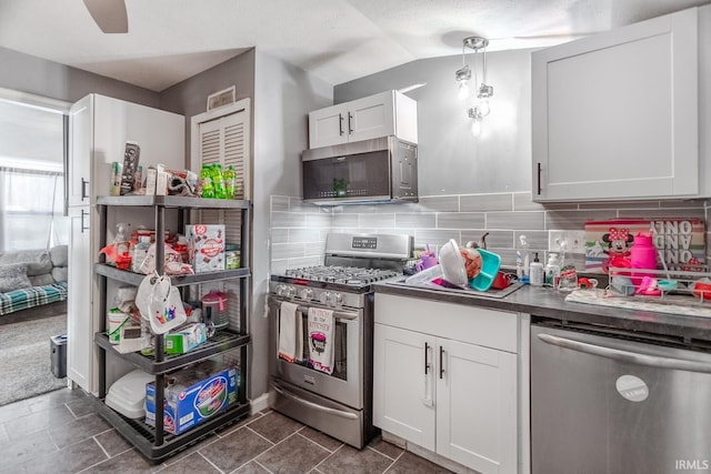 kitchen with lofted ceiling, decorative light fixtures, decorative backsplash, white cabinetry, and appliances with stainless steel finishes