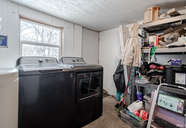 clothes washing area with a textured ceiling, washing machine and clothes dryer, and wooden walls