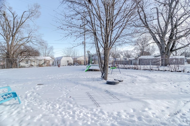 yard layered in snow featuring a storage unit and a trampoline