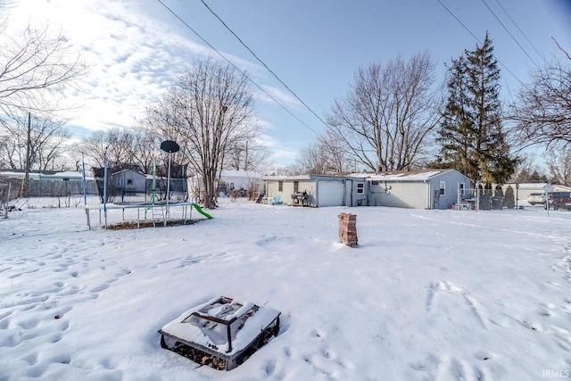 snowy yard featuring a garage and a trampoline