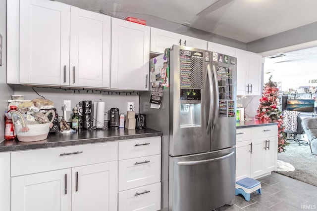 kitchen with light colored carpet, white cabinetry, and stainless steel fridge