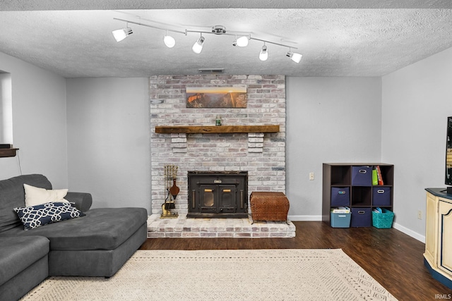 living room with a wood stove, a textured ceiling, and dark hardwood / wood-style flooring