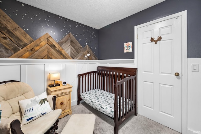 bedroom with light carpet, a textured ceiling, and a nursery area