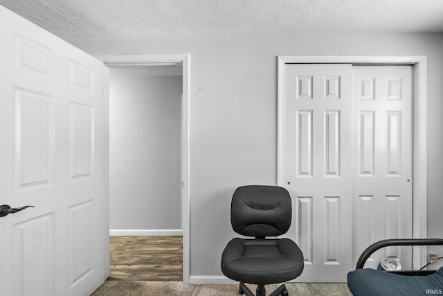 sitting room with a textured ceiling and dark colored carpet