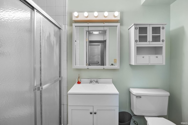 bathroom with toilet, a shower with shower door, and vanity