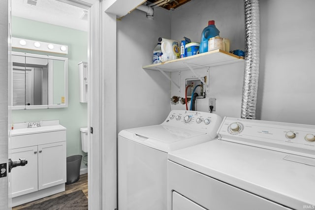 washroom with washing machine and dryer, dark hardwood / wood-style flooring, and sink