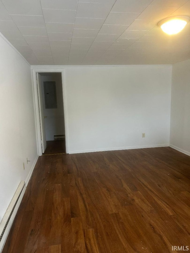 empty room featuring baseboard heating, dark wood-type flooring, and electric panel