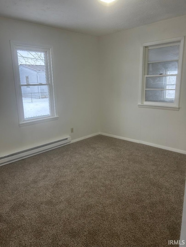 carpeted spare room featuring baseboard heating