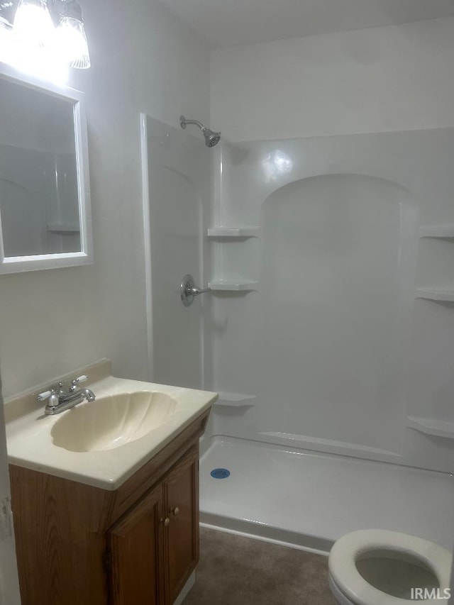 bathroom featuring walk in shower, vanity, and toilet