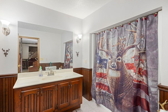 bathroom featuring a textured ceiling, tile patterned floors, wood walls, and vanity