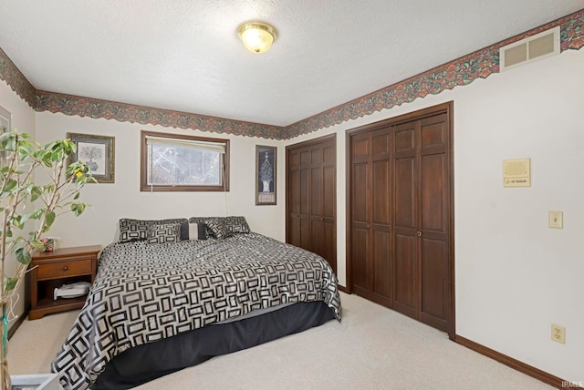 bedroom featuring carpet, a textured ceiling, and two closets