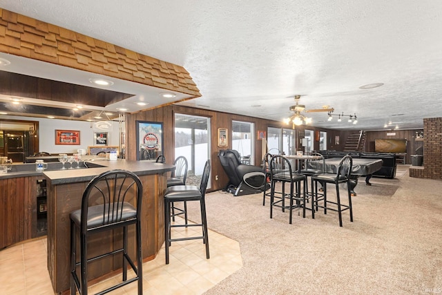 dining area featuring a textured ceiling, pool table, light carpet, wood walls, and ceiling fan