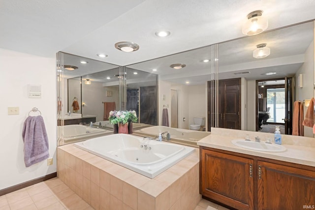 bathroom featuring tiled tub, tile patterned floors, vanity, and toilet