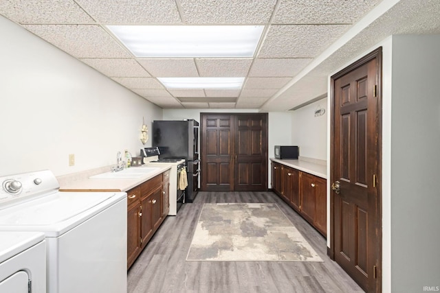 laundry area featuring light wood-type flooring, sink, and washer and dryer