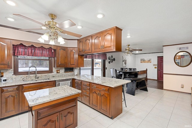 kitchen with a kitchen island, light stone counters, and sink